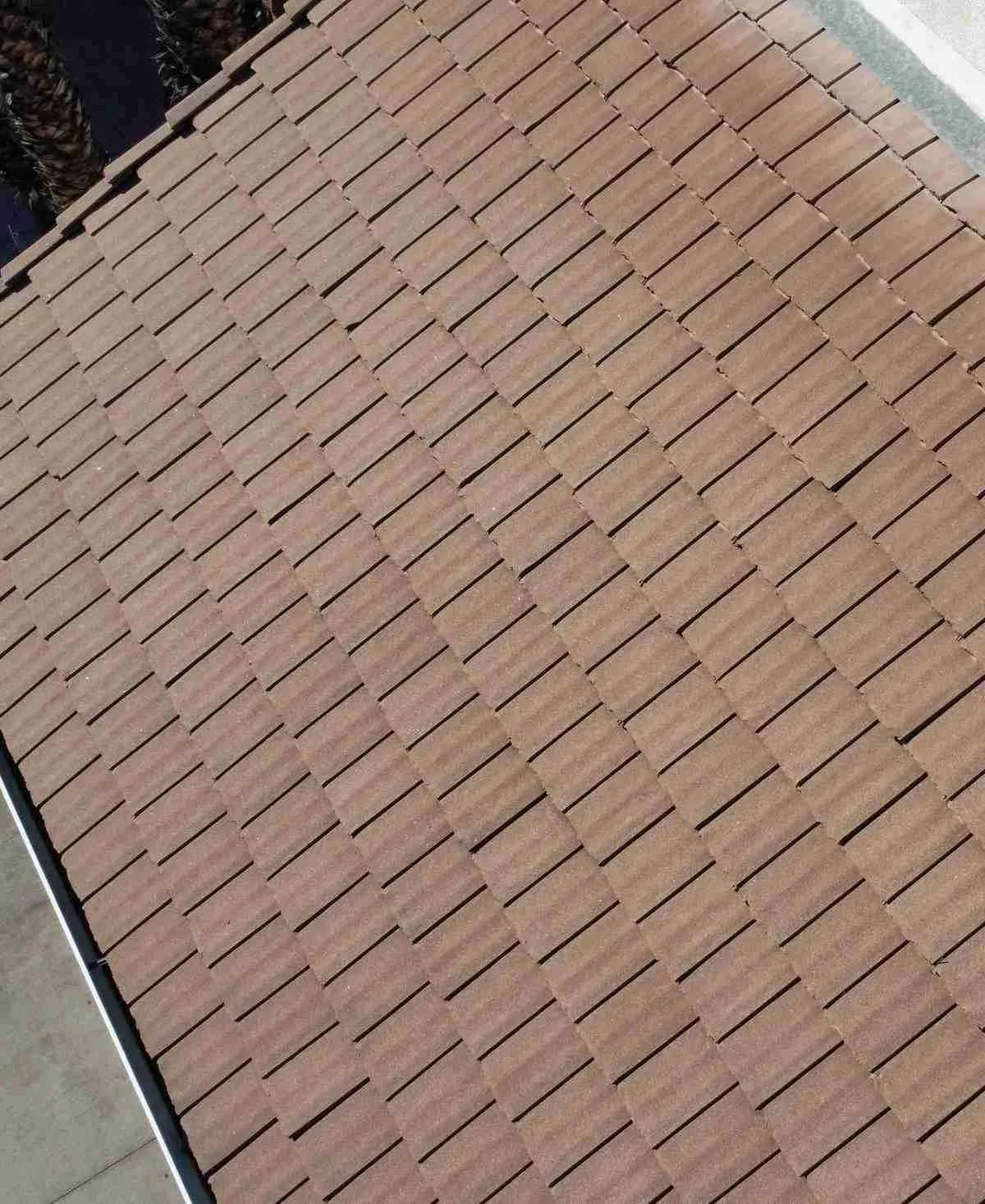 Aerial view of a brown interlocking tile roof next to a white stucco wall